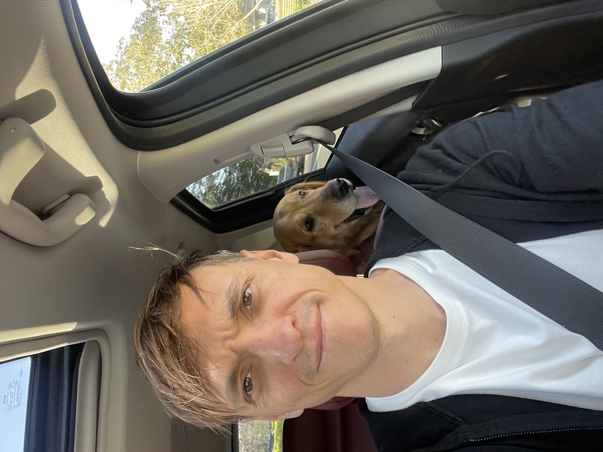 Andrei Novikov, founder of Merit, behind the wheel with a golden retriever in the back seat